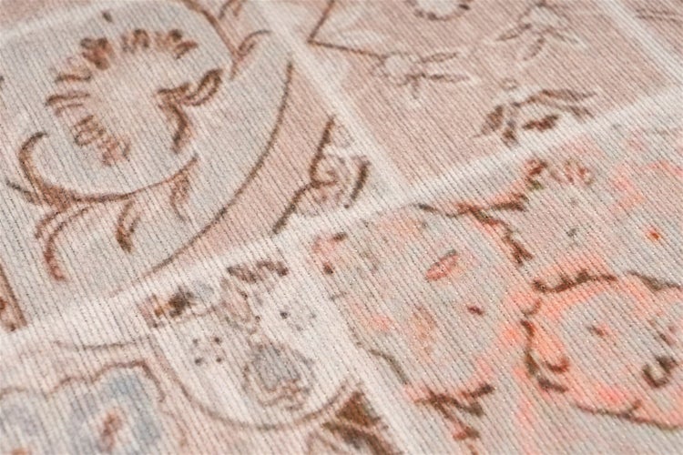 Nahaufnahme eines Teppichs mit Vintage-Patchwork-Muster, floralen Ornamenten und gerippter Webstruktur.
