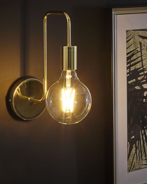 Goldene Wandleuchte mit dekorativer Glühbirne neben einem gerahmten Bild