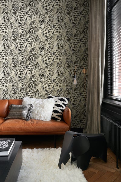 Wohnzimmer mit braunem Sofa, Kissen und Tapete mit Palmenmuster