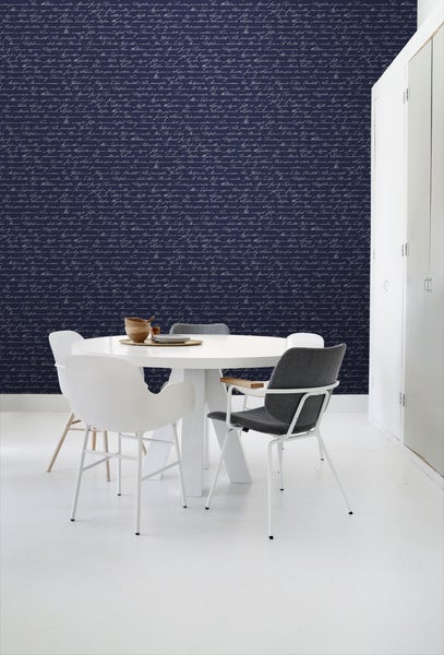 Esszimmer mit Esstisch und Stühlen vor einer Wand mit Tapete mit Schriftmuster