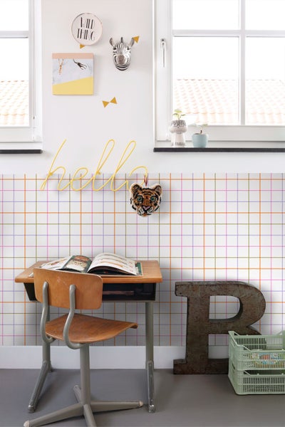 Hell eingerichtetes Kinderzimmer mit mehrfarbig karierter Tapete, Holzschreibtisch und verspielten Wanddekorationen.