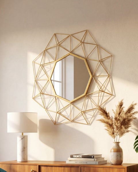 Geometrischer Wandspiegel mit goldenem Metallrahmen in kristallinem Design über einer Holzkommode.