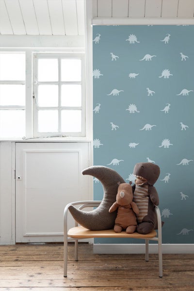 Kinderzimmer mit Dinosaurier-Tapete, Mondkissen und Plüschtieren auf einem Stuhl