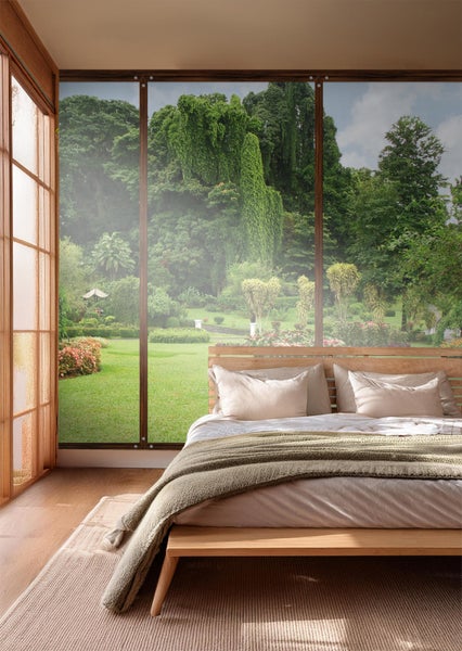 Helles Schlafzimmer mit Bett vor großem Fenster mit Gartenblick