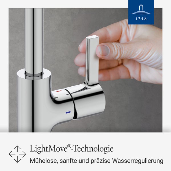 Villeroy und Boch Logo. Eine moderne Küchenarmatur mit hohem Auslauf an einer Spüle vor einem großen Fenster mit Ausblick.