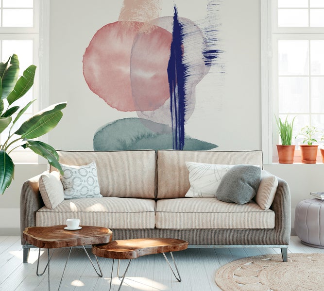 Modernes Wohnzimmer mit einer Fototapete mit abstrakten Aquarell-Formen über einem beigen Sofa und Holz-Couchtischen.