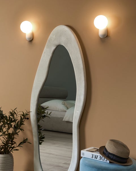 Dekoratives Zimmer mit Stehspiegel, Wandleuchten, Zimmerpflanze, Hocker, Buch und Hut