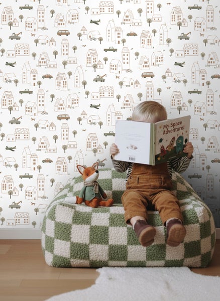 Kind liest Buch auf einem Sitzsack vor einer Tapete mit Stadtmotiven