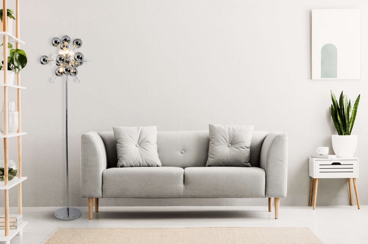 Helles Wohnzimmer mit Sofa, Stehlampe und Regal.