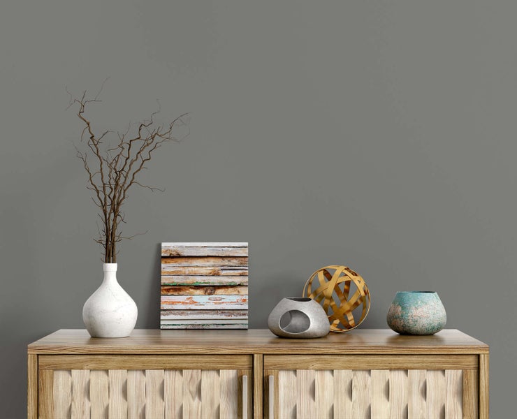 Matt graue Wandfarbe in einem modern dekorierten Raum mit Holzkommode und dekorativen Objekten wie einer Vase und Zweigen.