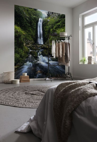 Schlafzimmer mit Fototapete eines Wasserfalls, Kleiderständer und rundem Teppich