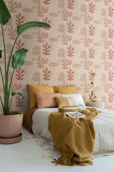 Schlafzimmer mit gemusterten Tapeten, Bett, Kissen und Zimmerpflanze