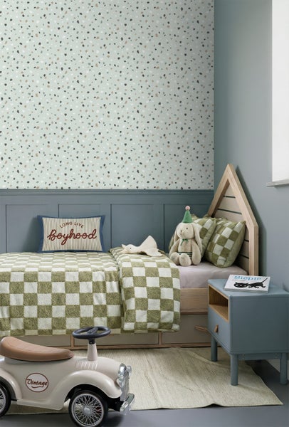 Kinderzimmer mit Terrazzo-Tapete, dunkelblauer Wandtäfelung, hölzernem Hausbett, karierter Bettwäsche und einem Vintage-Rutscher.