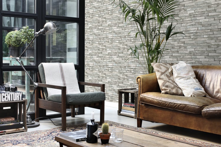 Wohnzimmer mit Sessel, Sofa, Stehlampe und dekorativer Steinwand