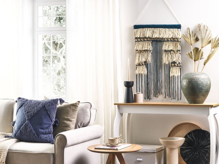 Dekoratives Wohnzimmer mit Sofa, Kissen, Wandbehang und Tischdekoration