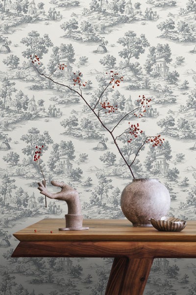 Dekoratives Zimmer mit gemusterter Tapete, Holztisch, Vase und dekorativen Accessoires.