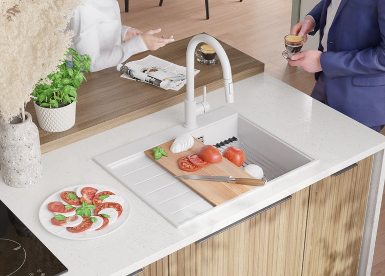 Küchenspüle mit Armatur, Schneidebrett mit Tomaten und Mozzarella auf einer Küchenarbeitsplatte.