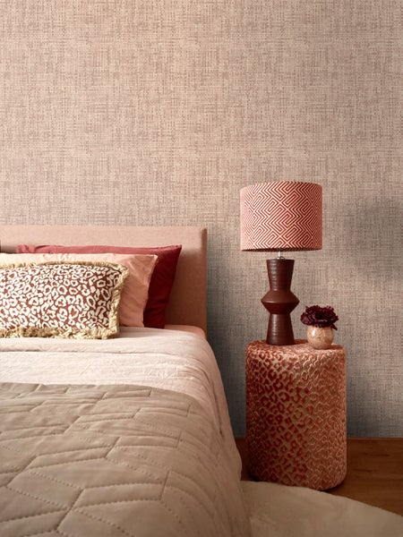 Blick auf ein Schlafzimmer mit einem Bett, einem Nachttisch mit Lampe und einer strukturierten Tapete