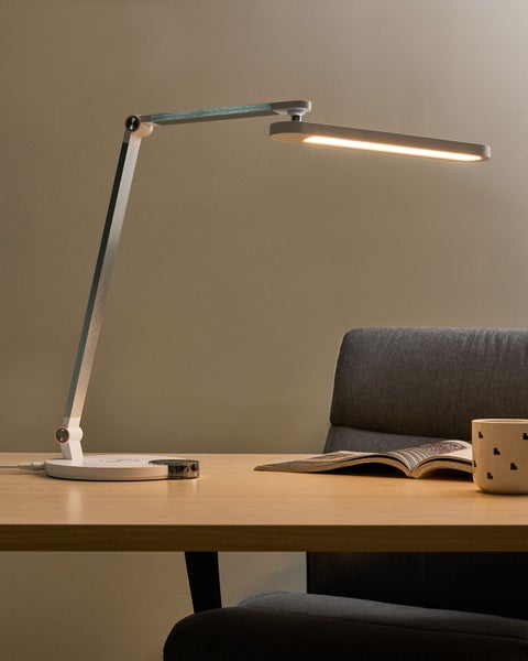 LED-Tischleuchte auf einem Schreibtisch mit Buch und Tasse.