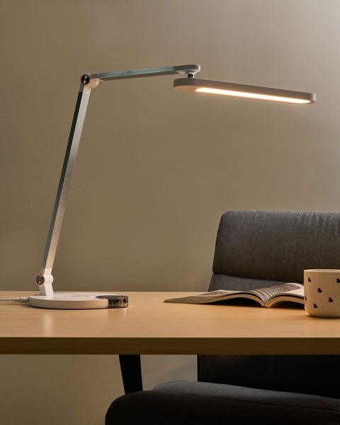 LED-Schreibtischlampe auf einem Schreibtisch mit Buch und Tasse