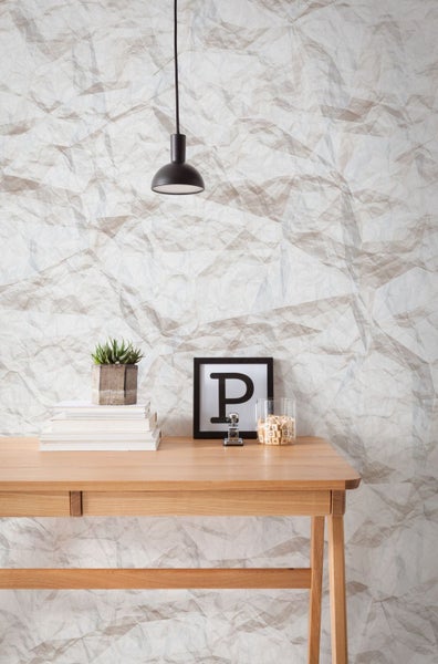 Büro mit Schreibtisch, Büchern, Pflanze, Dekoration und Pendelleuchte vor einer Tapete mit Papierstruktur