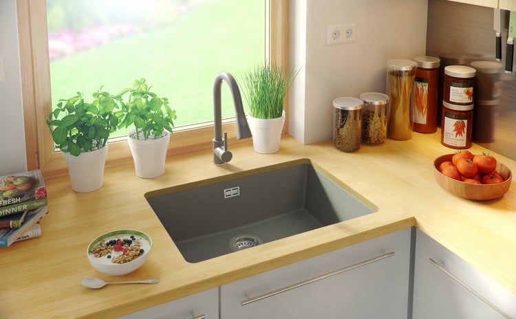 Küchenspüle in einer hellen Küche mit Frühstück und Kräutern