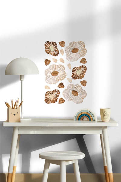 Szene mit einem Schreibtisch, einer Lampe, Stiften, einem Regenbogen, einer Tasse und hölzernen Blumenwandaufklebern an einer Wand.