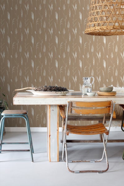 Dekoratives Interieur mit einem Esstisch vor einer Wand mit Gräser-Motiv-Tapete.