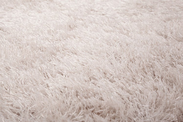 Detailaufnahme eines cremefarbenen Hochflor-Teppichs mit dichten, weichen Kunstfasern.