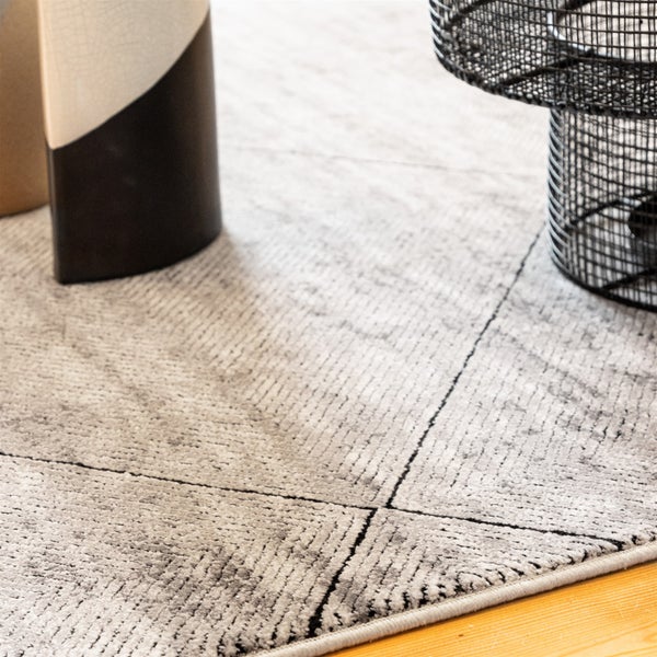 Moderner Kurzflorteppich mit geometrischem Linienmuster auf Holzboden neben einem Beistelltisch.