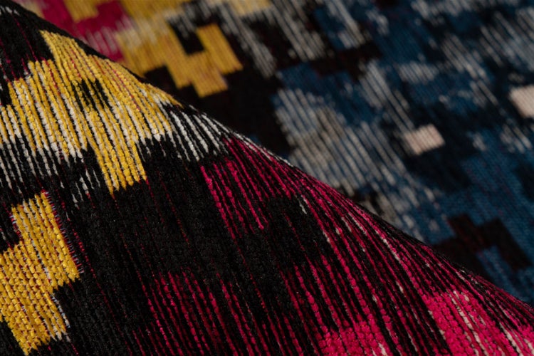 Nahaufnahme eines gewebten Teppichs mit buntem geometrischem Muster und weicher Struktur.