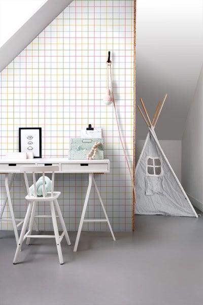 Hell gestalteter Kinderbereich mit bunter Karo-Vliestapete an der Wand, weißem Schreibtisch und gestreiftem Spielzelt.