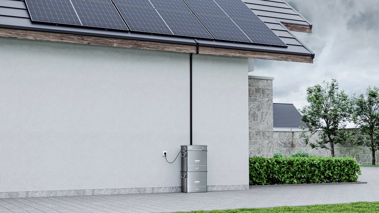 Zendure Speichersystem an einer Hauswand im Außenbereich, verbunden mit Solarmodulen auf dem Dach eines Wohnhauses.