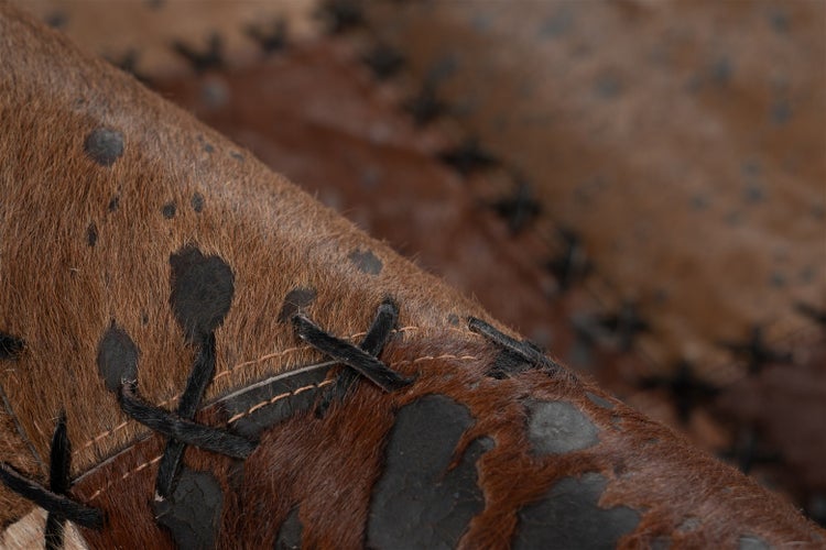 Nahaufnahme eines Patchwork-Teppichs aus Kuhfell mit dekorativen Kreuzstichen.