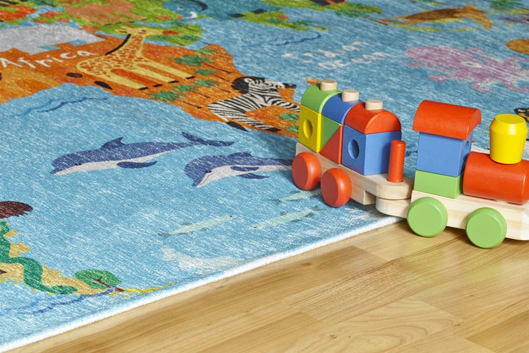 Kinderteppich mit Weltkarte und Tiermotiven, Holzeisenbahn auf hellem Holzboden.