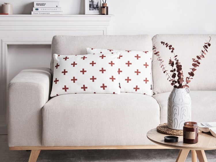 Wohnzimmer-Szene mit Sofa, Kissen mit Kreuzmuster, Tisch, Vase und Dekoration