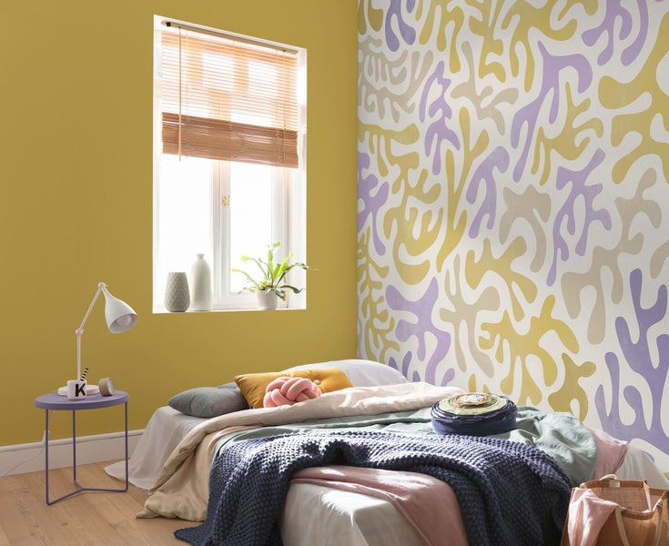 Helles Schlafzimmer mit gemusterten Tapeten und Holzbett