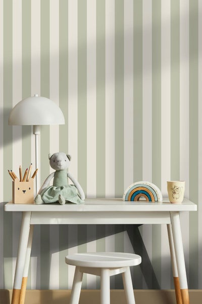 Gestreifte Tapete in Salbeigrün und Creme hinter einem weißen Kinderschreibtisch mit passendem Hocker, Spielzeug und einer Tischlampe.