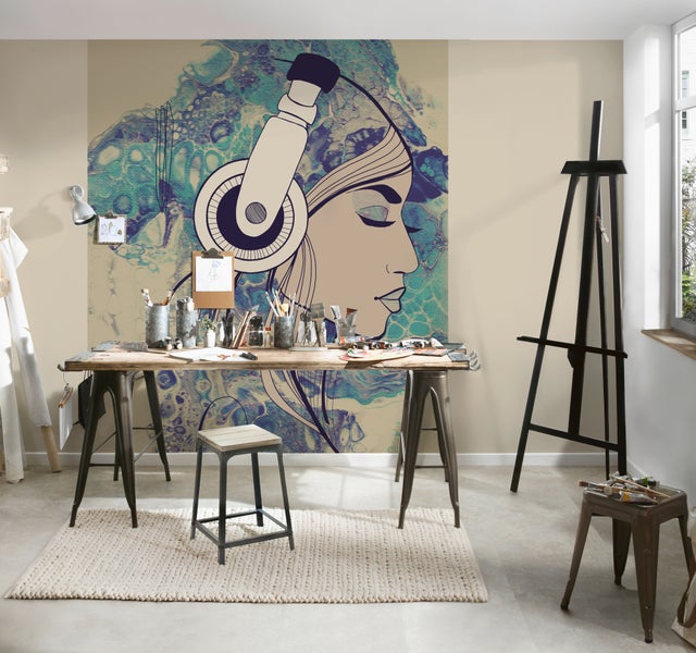 Vlies-Fototapete mit Kunstmotiv einer Frau mit Kopfhörern in einem modern eingerichteten Künstleratelier mit Arbeitstisch und Staffelei.