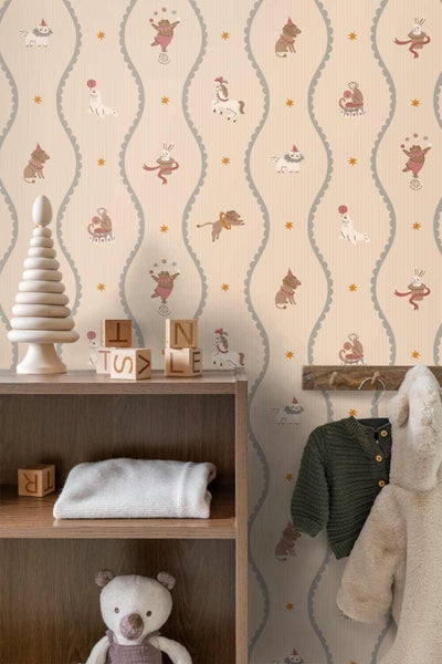 Kinderzimmer mit Vliestapete mit Zirkusmotiven wie Bären und Affen, einem Holzregal mit Spielzeug sowie Kleidung an einer Garderobe.