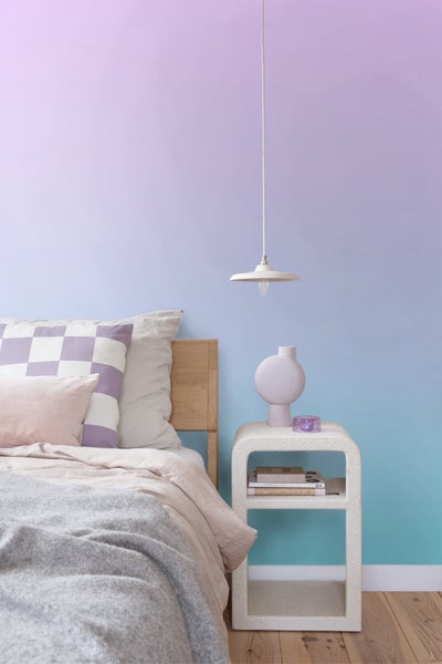 Schlafzimmer mit Bett, Nachttisch, Lampe und dekorativen Elementen für eine helle und organisierte Atmosphäre.