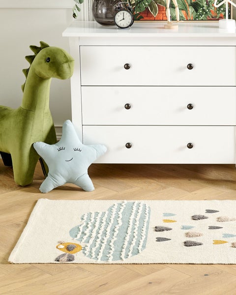 Kinderteppich mit Wolkenmotiv und Regentropfen auf Parkettboden in einem hellen Kinderzimmer mit weißer Kommode und Dinosaurier-Stofftier.