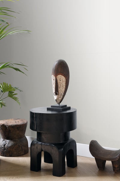 Dekorative Holzmaske auf einem schwarzen Beistelltisch in einem Interieur