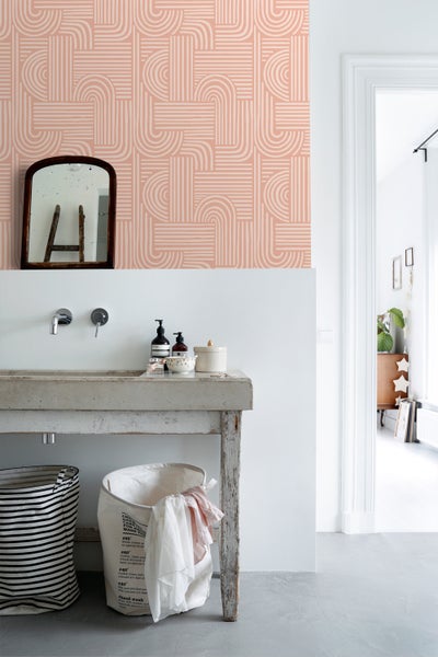 Badezimmer mit Waschbecken, Spiegel, gemusterter Tapete und Wäschekörben
