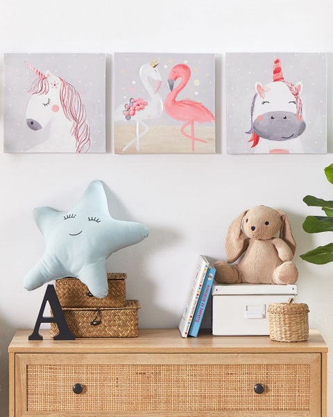 Kinderzimmerdekoration mit Einhorn und Flamingo Wandbildern, Sternkissen und Hasenkuscheltier auf einer Kommode