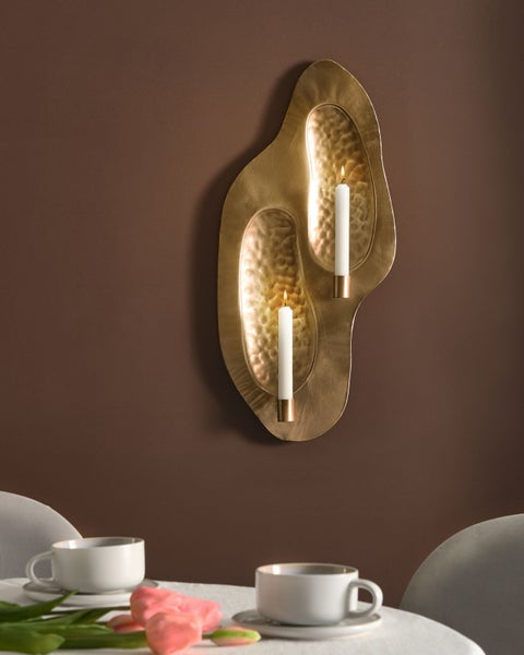 Dekorative Wandleuchte mit zwei Kerzenhaltern an einer Wand montiert.
