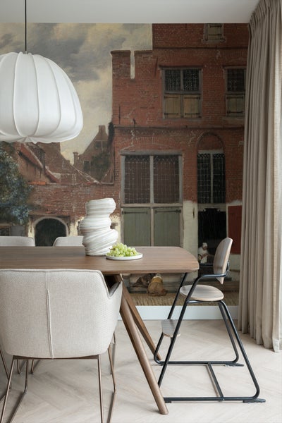 Esszimmer mit Esstisch, Stühlen, Lampe und Wandbild mit Stadtansicht