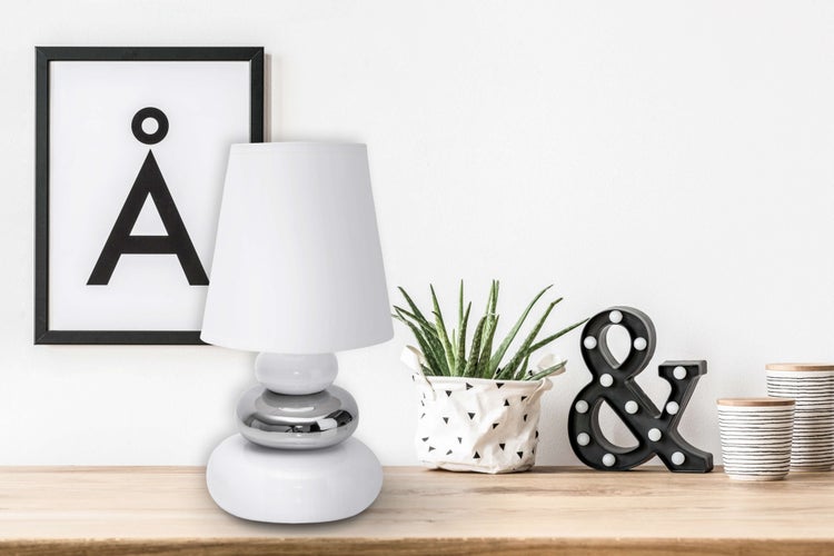 Dekorative Tischleuchte mit Stoffschirm auf einem Holztisch mit Dekorationen