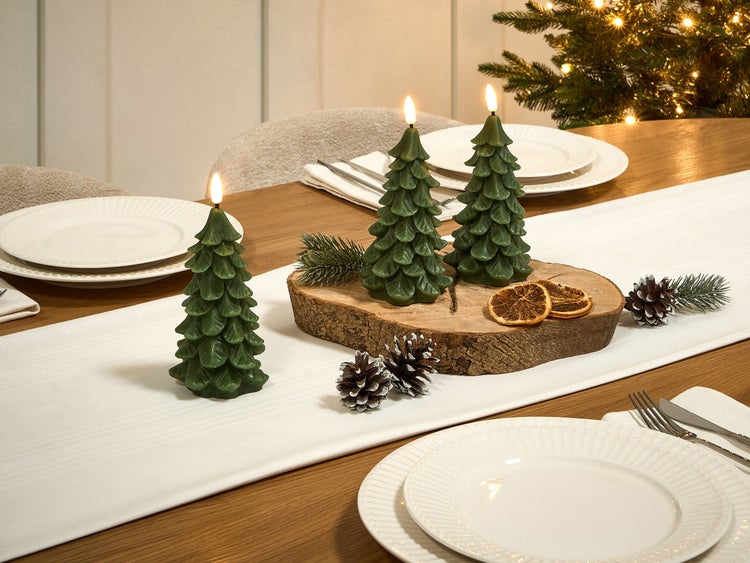 Festlicher Tisch mit Baumkerzen, Tannenzapfen und Baumschmuck für Weihnachten.