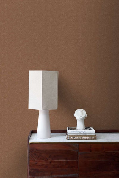 Strukturierte Tapete mit Fischgrätmuster an einer Wand kombiniert mit einem Sideboard aus Holz und Marmor sowie einer Tischlampe.